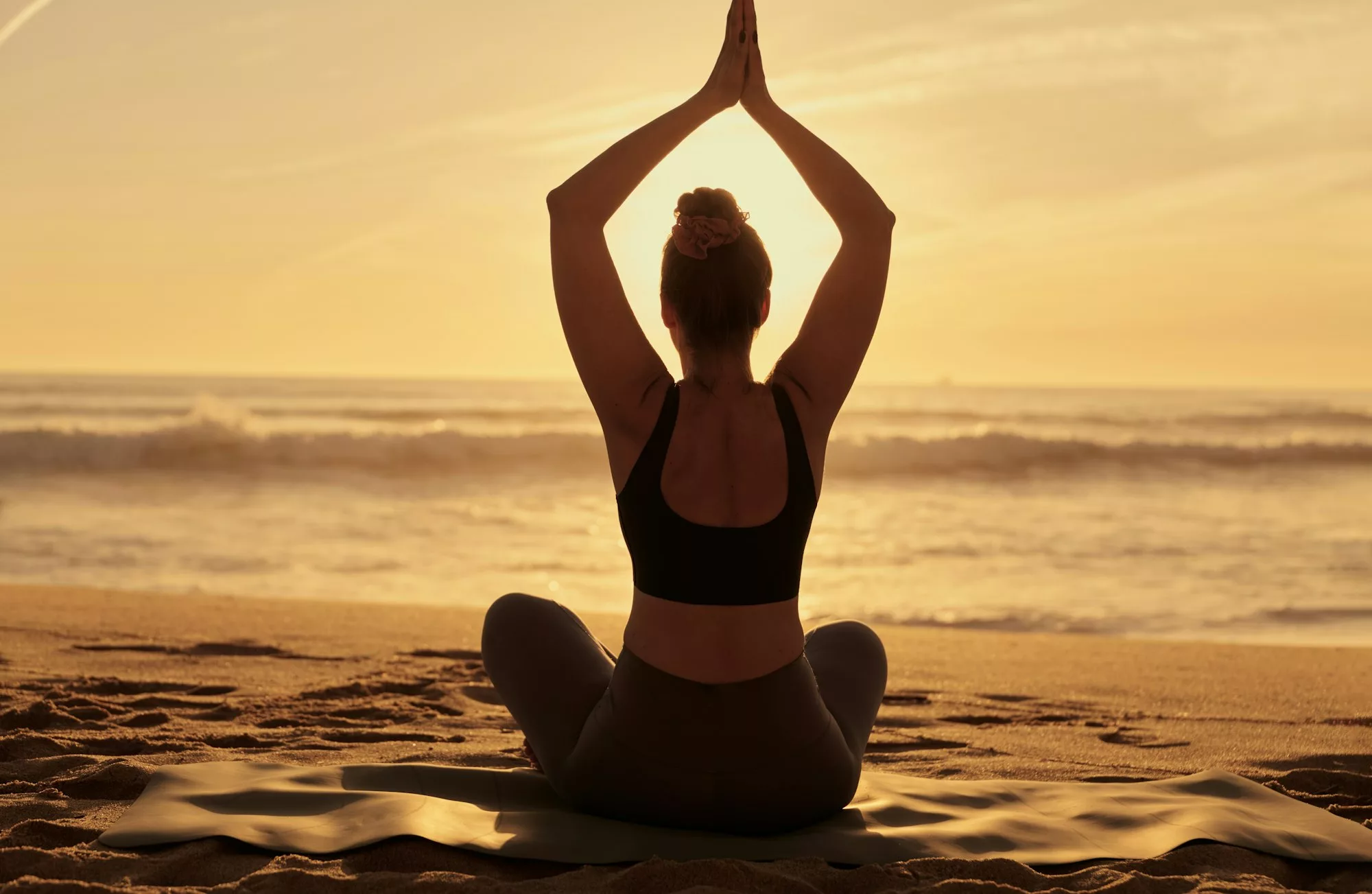 Slim woman doing yoga with raised arms