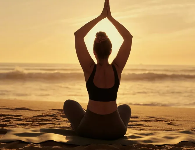 Slim woman doing yoga with raised arms